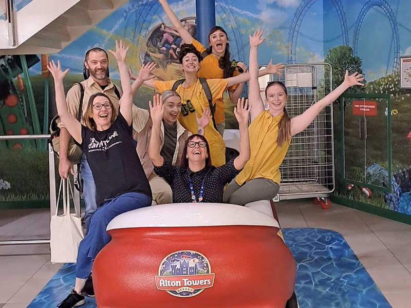 Several people posing inside a roller coaster cart that's situated within a hospital